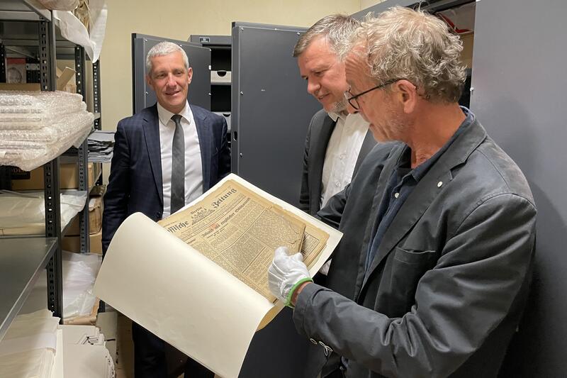 Dr. Peter Böthig zeigt eine fast hundert Jahre alte Zeitung, in der Texte von Tucholsky erstmals veröffentlicht wurden. © Landkreis OPR