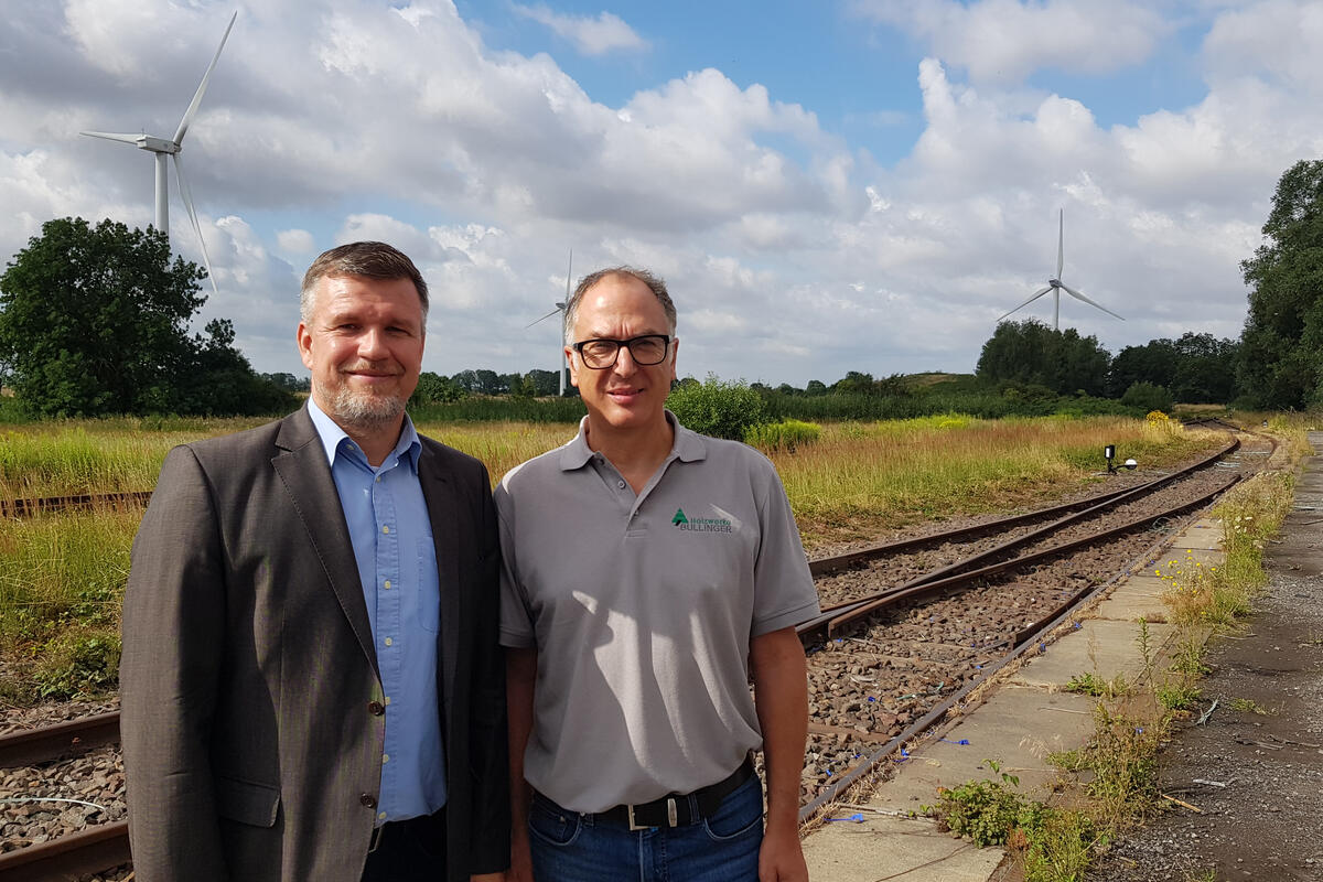 Landrat Ralf Reinhardt und Andreas Bullinger stehen an den Gleisen, über die die Firma Bullinger beliefert wird. © Landkreis OPR